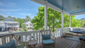 A covered porch with wicker furniture, a view of houses, and a clear sky. - The Sassy Seahorse: Spacious Beach Home with Multiple Living Areas and Room for (Oak Island)