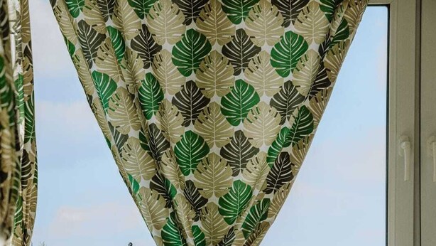 Un balcó amb una cadira blanca, una taula petita amb una planta en test i una cadira color esmeralda.