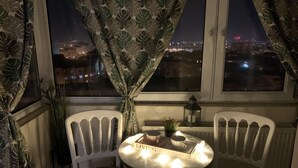 Un balcó amb dues cadires blanques, una taula petita amb un rètol que diu 'LIVING', una planta en test i un fanal.