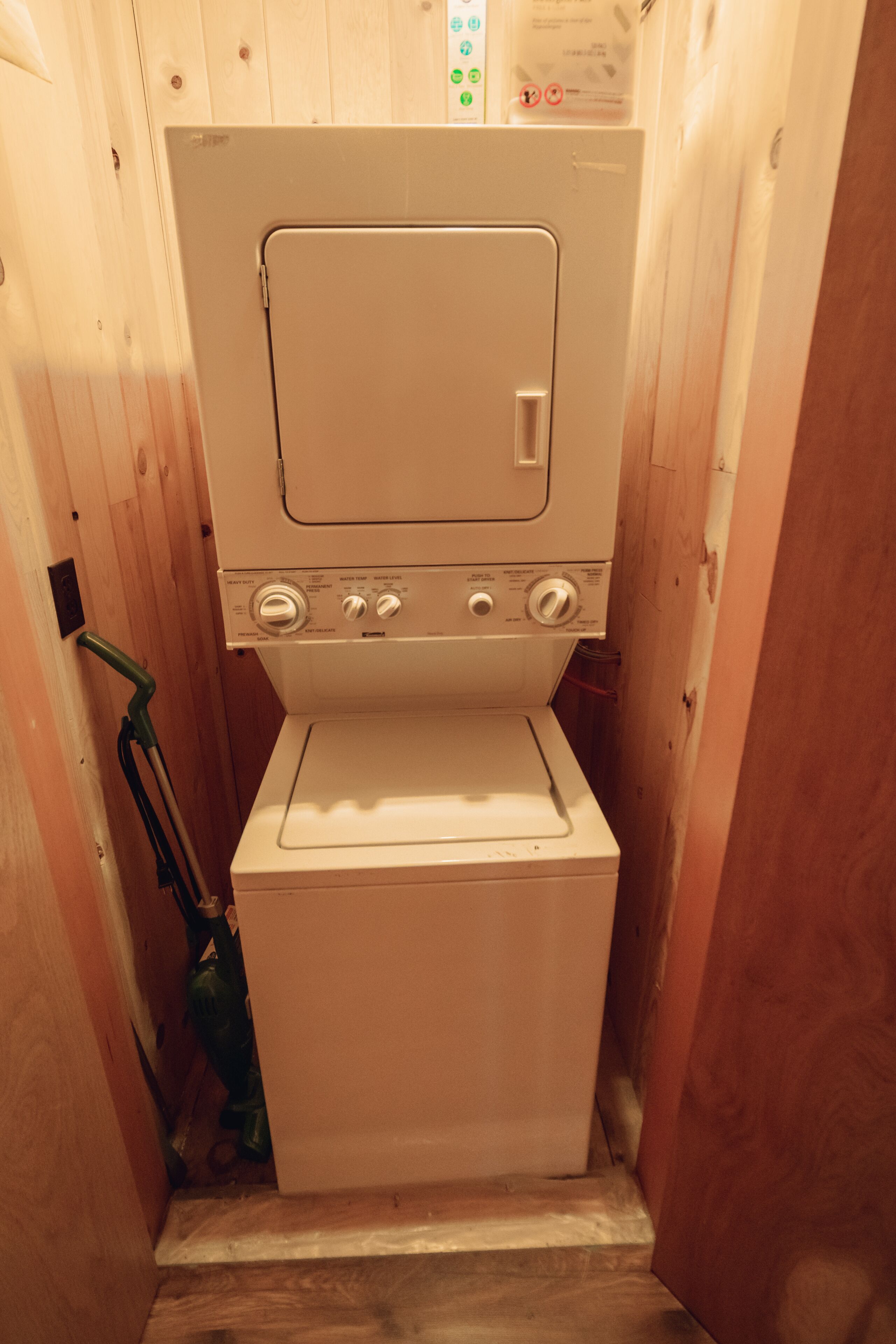 A compact, wooden-walled laundry room with a white washer and dryer.