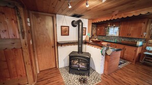 A cozy kitchen with wooden cabinets, a built-in stove, and a small island with a sink. - Riverside Mid-Century Cabin with Mountain Views (Baring)
