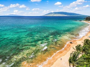 A beach with clear turquoise water, a sandy shore, and a mountain in the distance. - Remodeled Wailea Condo w AC Infinity Pool-Palms of Wailea 2108 (Kihei)