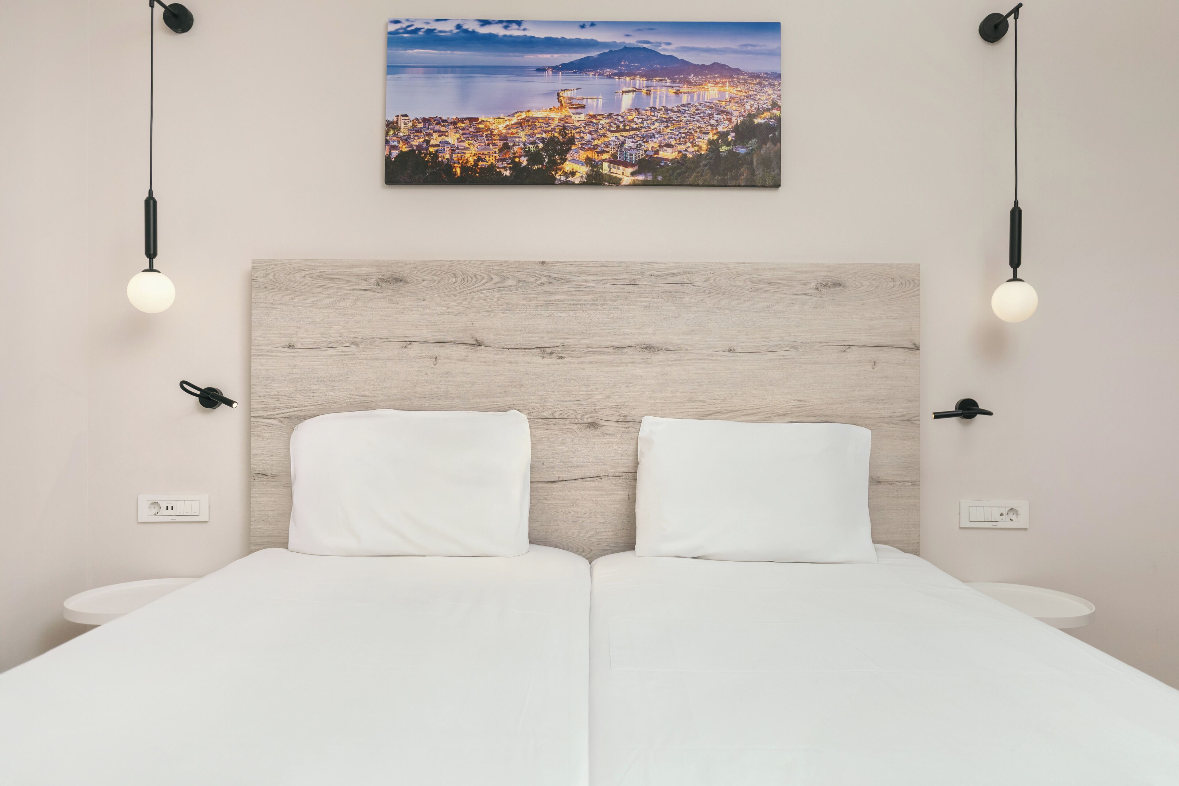 A double bed with white bedding, a wooden headboard, and two bedside tables.