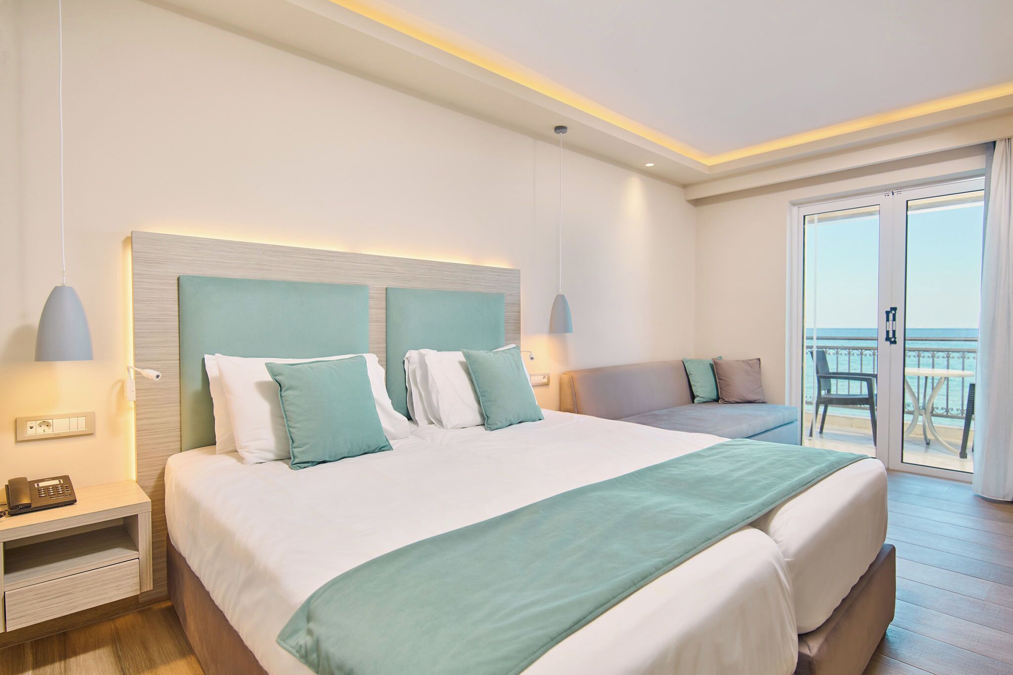 A modern hotel room with a large bed, a bedside table, a phone, and a view of the balcony.