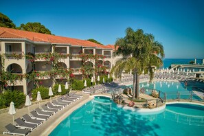 Un resort con piscina, tumbonas y vista al mar.