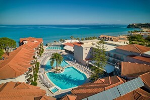 A resort with a large swimming pool surrounded by lounge chairs, a separate pool, and a view of the sea. - Tsilivi Beach Hotel (Zakynthos)