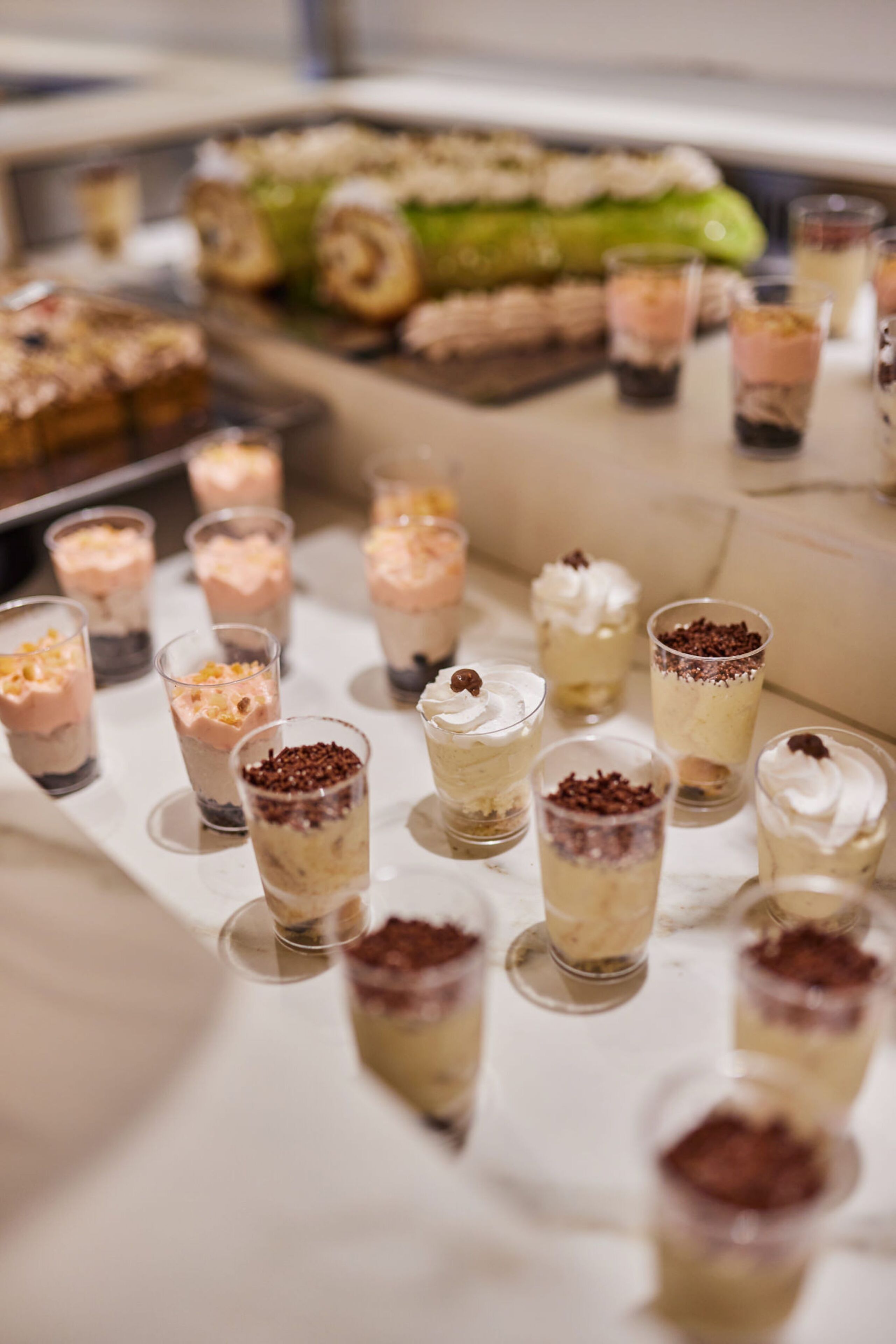 A dessert table with various layered desserts in small glasses.