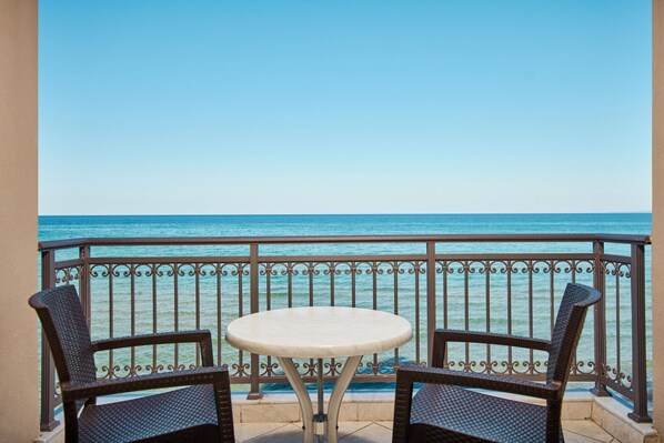 Un balcón con una mesa y dos sillas, con vista a un mar azul y despejado.