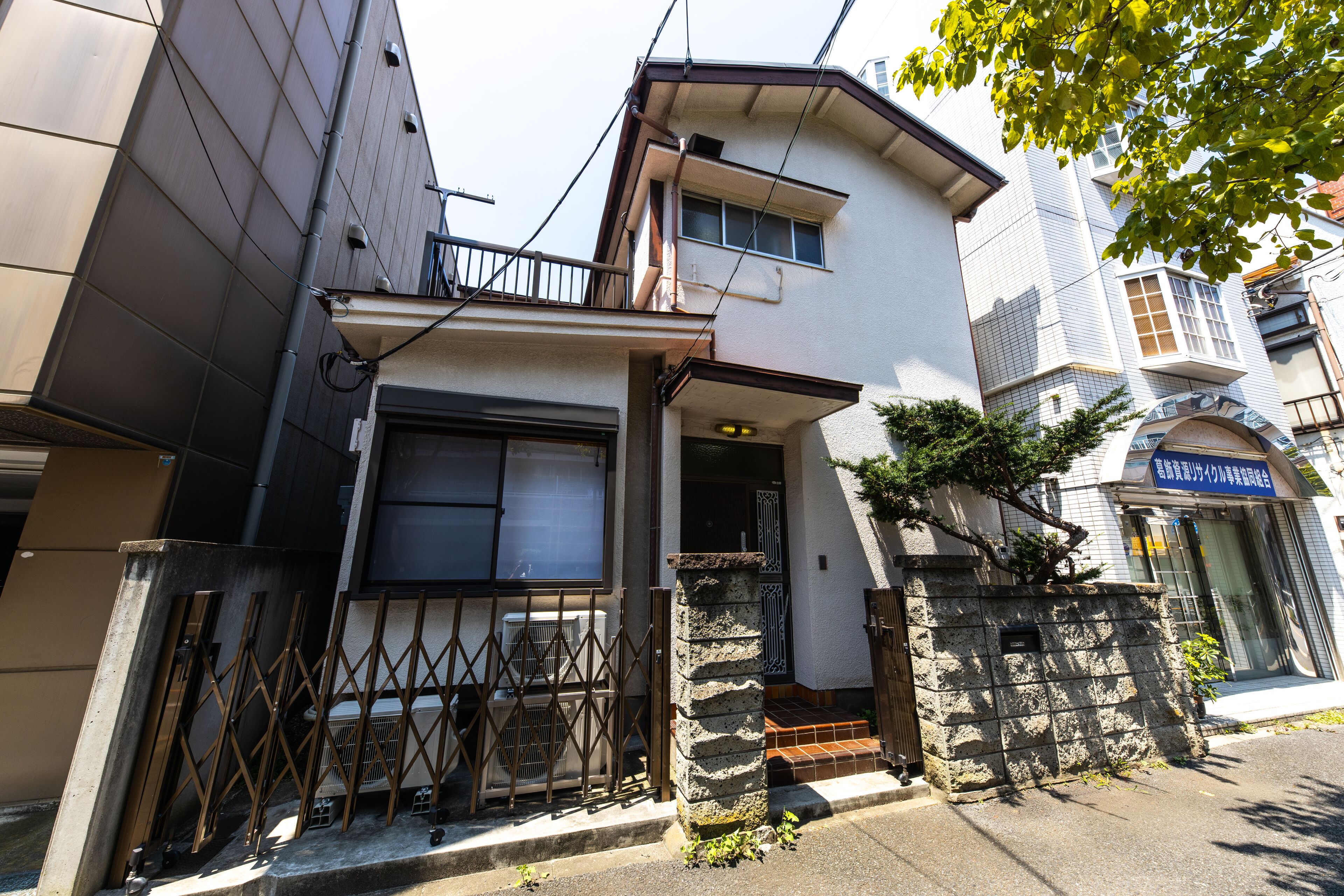A two-story building with a stone entrance, a metal gate, and a small porch.