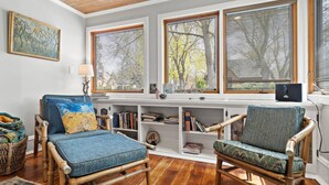 A cozy living room with two wooden chairs, a blue sofa, and a bookshelf filled with books. - Cozy North End Cottage! Walk the Tree-lined Neighborhood to Hyde Park + Camel's Back Park (Boise)