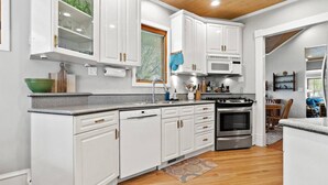 A modern kitchen with white cabinetry, a stainless steel stove, and a microwave. - Cozy North End Cottage! Walk the Tree-lined Neighborhood to Hyde Park + Camel's Back Park (Boise)