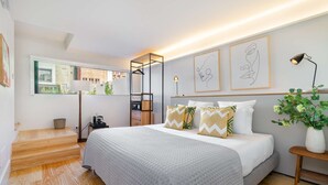 Un dormitorio moderno con una cama grande, mesitas de noche, un espejo y obras de arte en las paredes.