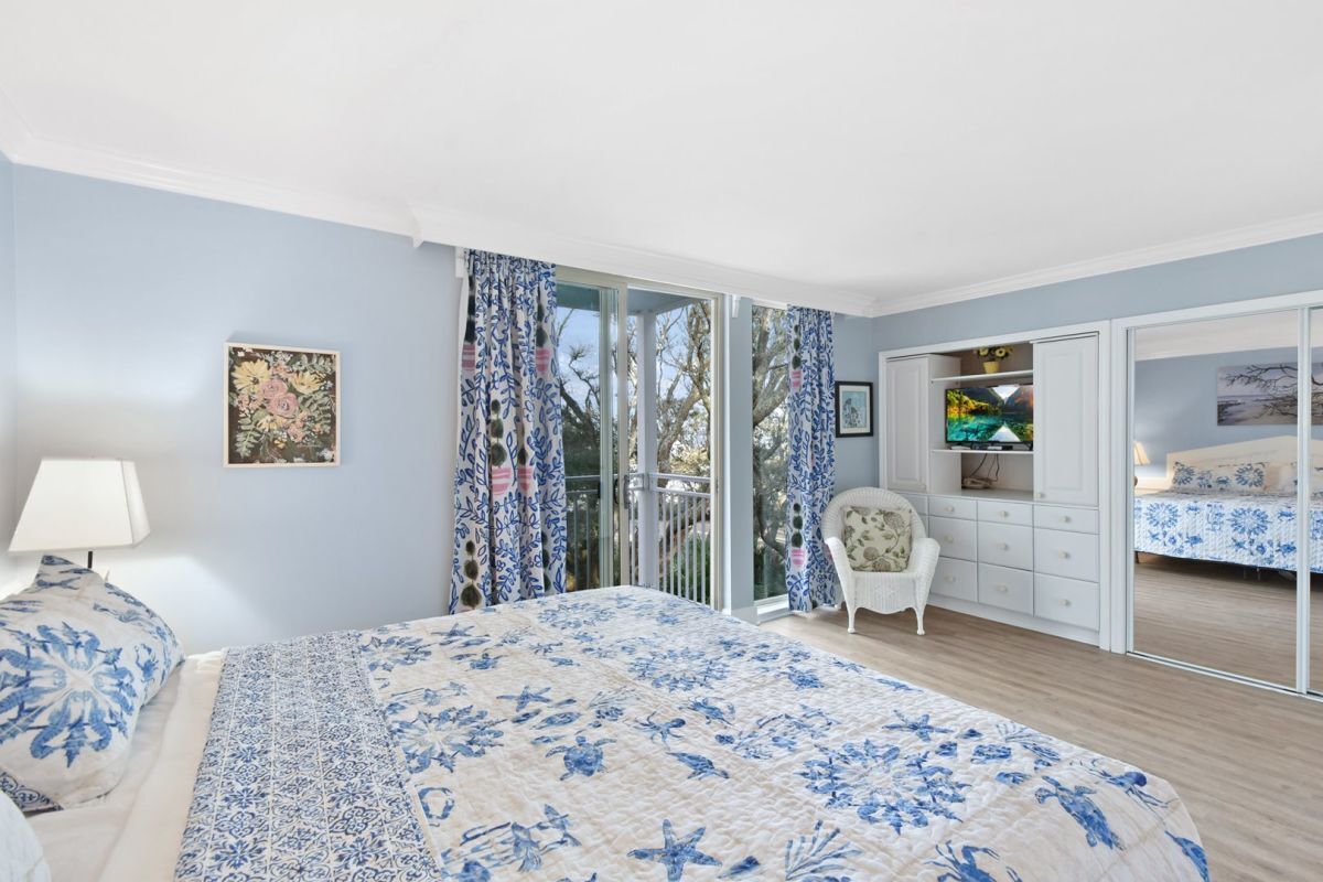 A bedroom with a large bed, a chair, a wardrobe, and a desk.