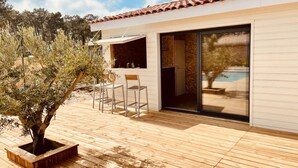 A modern house with a wooden deck, a dining area with chairs, and a sliding glass door leading to a pool.