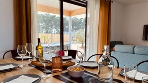 A dining table set for four with wine glasses, plates, cutlery, and a bottle of olive oil.