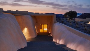 Una escalera que lleva a una habitación con vistas a la puesta de sol y montañas.