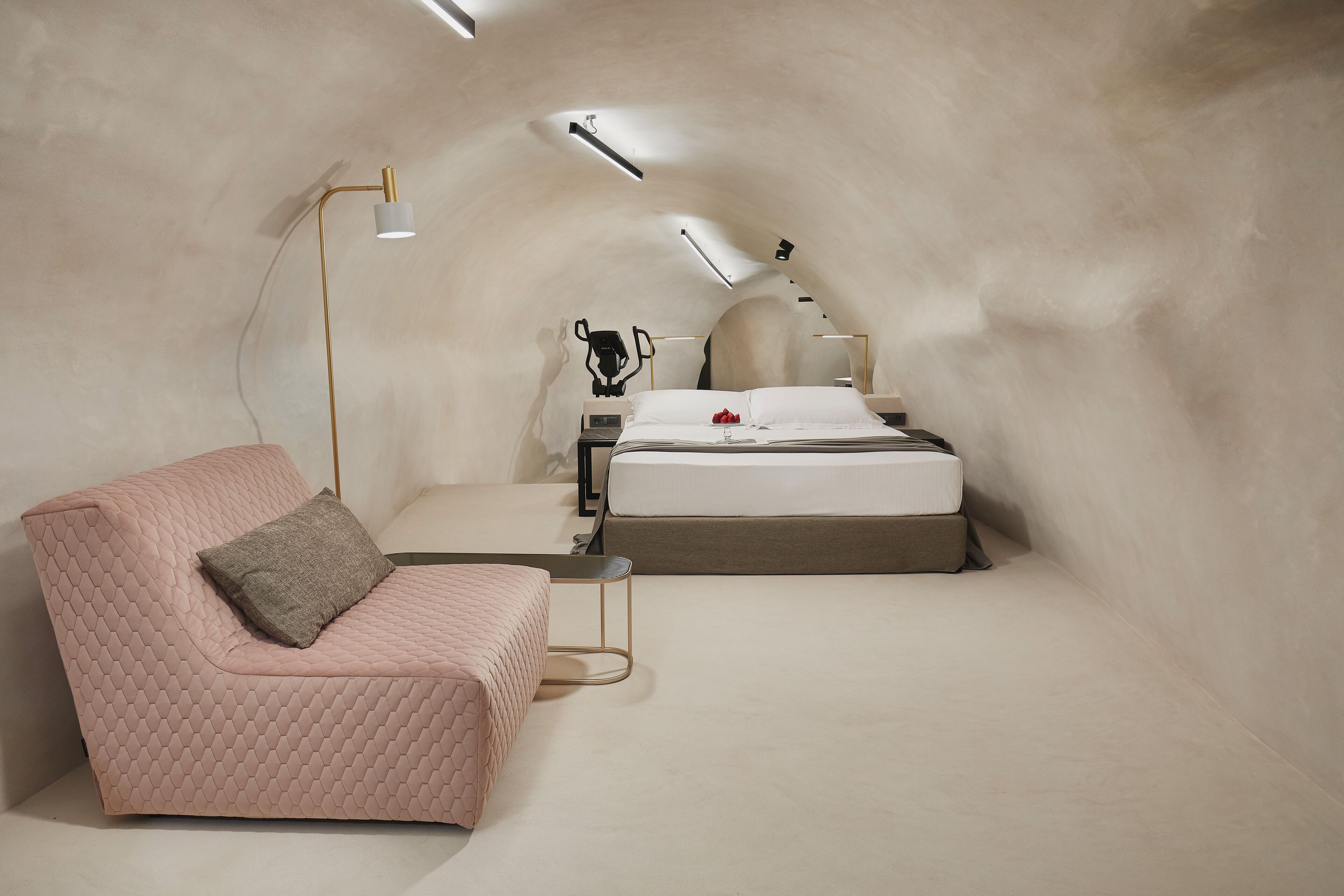 A cozy, modern bedroom with a pink sofa, a bed, and a small table.