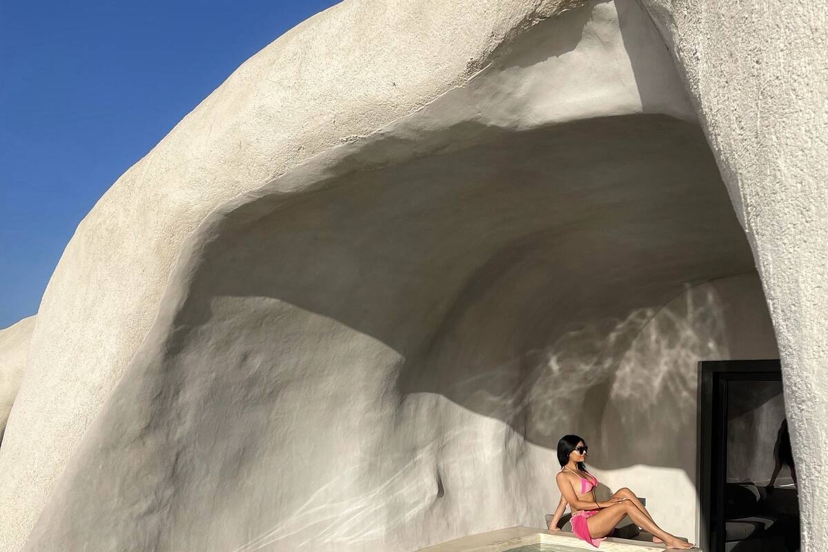 A person sitting by a pool in a white, cave-like structure.