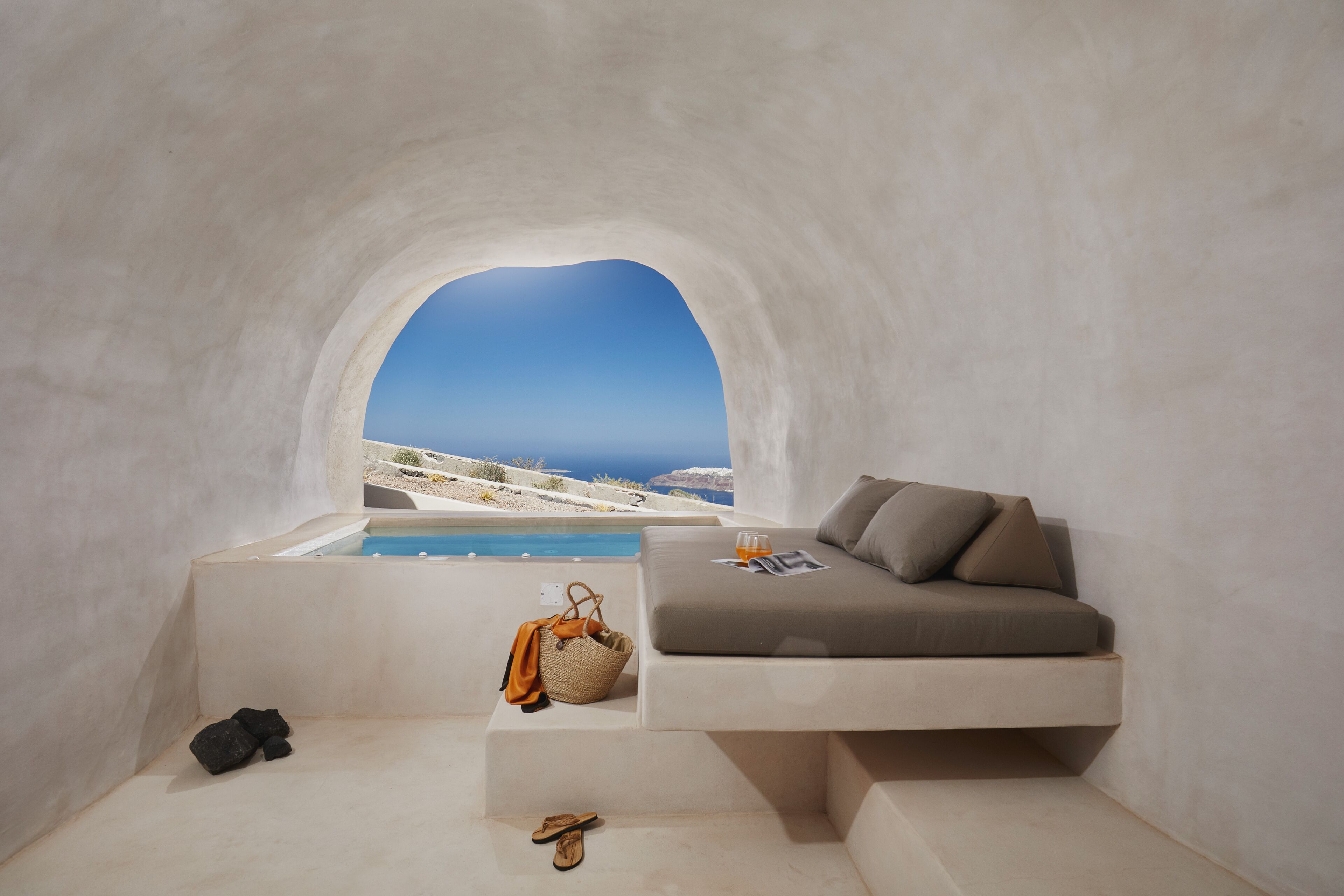 A modern, minimalist room with a built-in sofa and a window overlooking a pool and a scenic landscape.