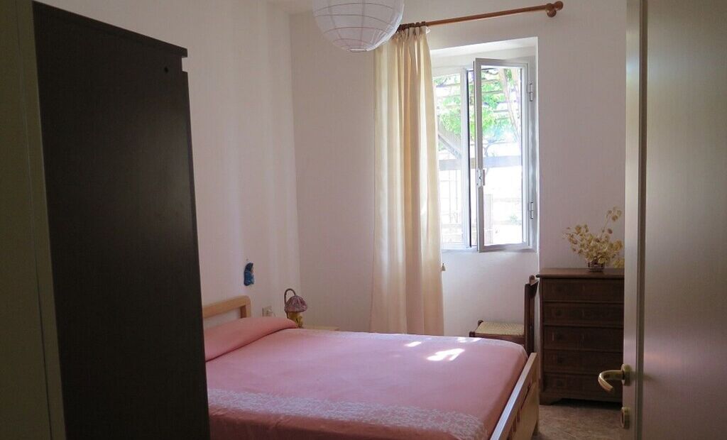Une chambre à coucher avec un lit, une commode, une fenêtre avec des rideaux et une porte.