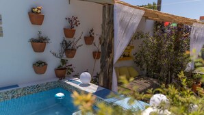 Un espace piscine doté d’un sol carrelé, entouré de plantes en pot et agrémenté d’une structure en bois.