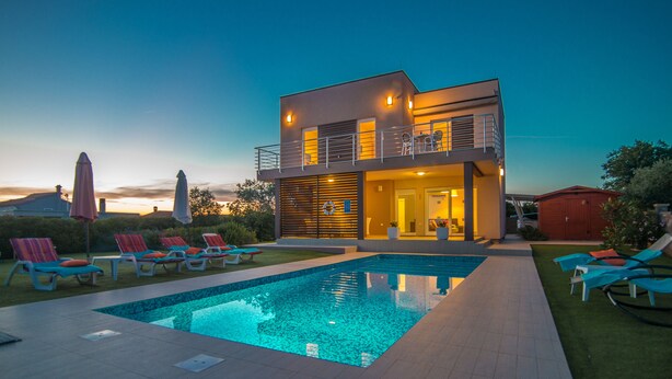 Ein modernes, zweistöckiges Haus mit Swimmingpool, Außenbereich und einer gut beleuchteten Eingangspartei.