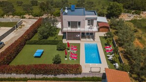 Ein modernes, zweistöckiges Haus mit Swimmingpool, Solaranlage und einem gepflegten Garten.