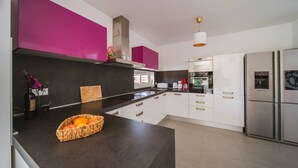 Eine moderne Küche mit weißen Schränken, einer schwarzen Arbeitsplatte und einem Edelstahl-Kühlschrank.