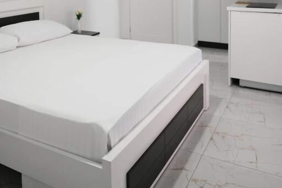 A bedroom with a bed, a bedside table, a nightstand, a wardrobe, and a door.