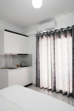Una cocina moderna con armarios blancos, salpicadero de mármol y un lavamanos empotrado.