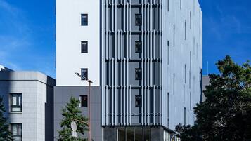 Ett modernt hotell med en vertikal design, flera våningar och en framträdande entré med en skylt.
