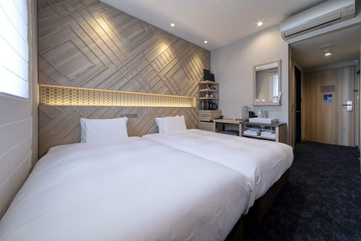 Ein Hotelzimmer mit einem großen Bett, einem Schreibtisch, einem Spiegel und einer Wand mit geometrischem Muster.