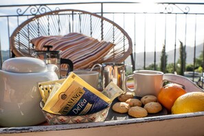 Una bandeja de desayuno con bolsitas de té, galletas, una naranja y una taza en un balcón.