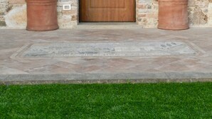 A stone building with a wooden door, two potted plants with flowers, and a small window to the left. - Villa "Il Grillo", privacy in the hills, private pool and panoramic view. (Toscana)