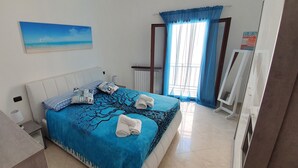 Une chambre à coucher bien rangée, avec un lit, un globe terrestre et un tableau représentant une scène de plage.