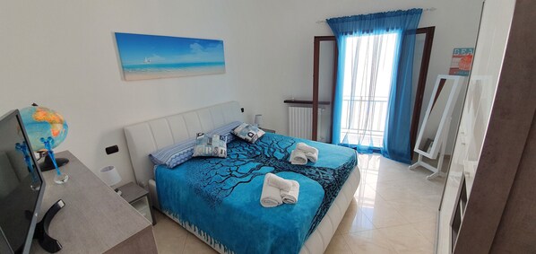 A neatly arranged bedroom with a bed, a globe, and a painting of a beach scene.