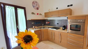 Une cuisine moderne avec des meubles en bois, des appareils électroménagers en acier inoxydable, un pare-feu en carrelage et une grande fenêtre avec des rideaux.