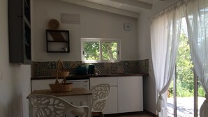 A compact kitchen with a window, a tiled backsplash, and a dining area with two chairs.