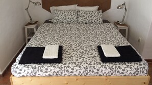 A neatly made bed with a patterned bedspread, two bedside lamps, and a headboard with a geometric design.