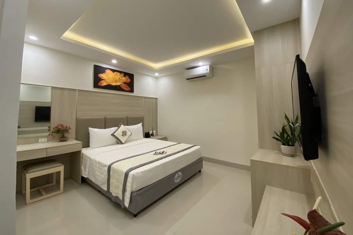 A modern bedroom with a bed, bedside table, mirror, and a mounted TV.