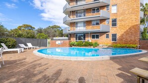 A multi-story building with a swimming pool, outdoor seating, and a fenced area. - Albacore 6, 12-14 Ondine Close (Nelson Bay)