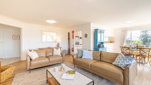 A spacious living area with two leather sofas, a coffee table, and a dining table set for four. - Albacore 6, 12-14 Ondine Close (Nelson Bay)