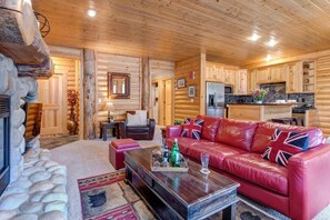 L’intérieur d’une cabane en rondins comprend un salon, une cuisine et une cheminée en pierre.