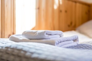 A neatly made bed with a folded white towel and a textured blanket. - Hotelli Uninen Tampere (Tampere)