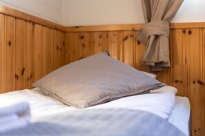 A single bed with a beige pillow and a wooden headboard in a room with wooden paneling. - Hotelli Uninen Tampere (Tampere)