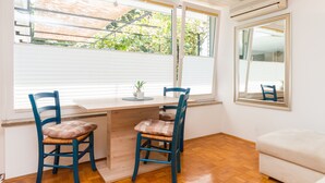 A room with a wooden desk, two chairs, a small potted plant, and a large mirror on the wall. - Apartments Kolenc (Piran)