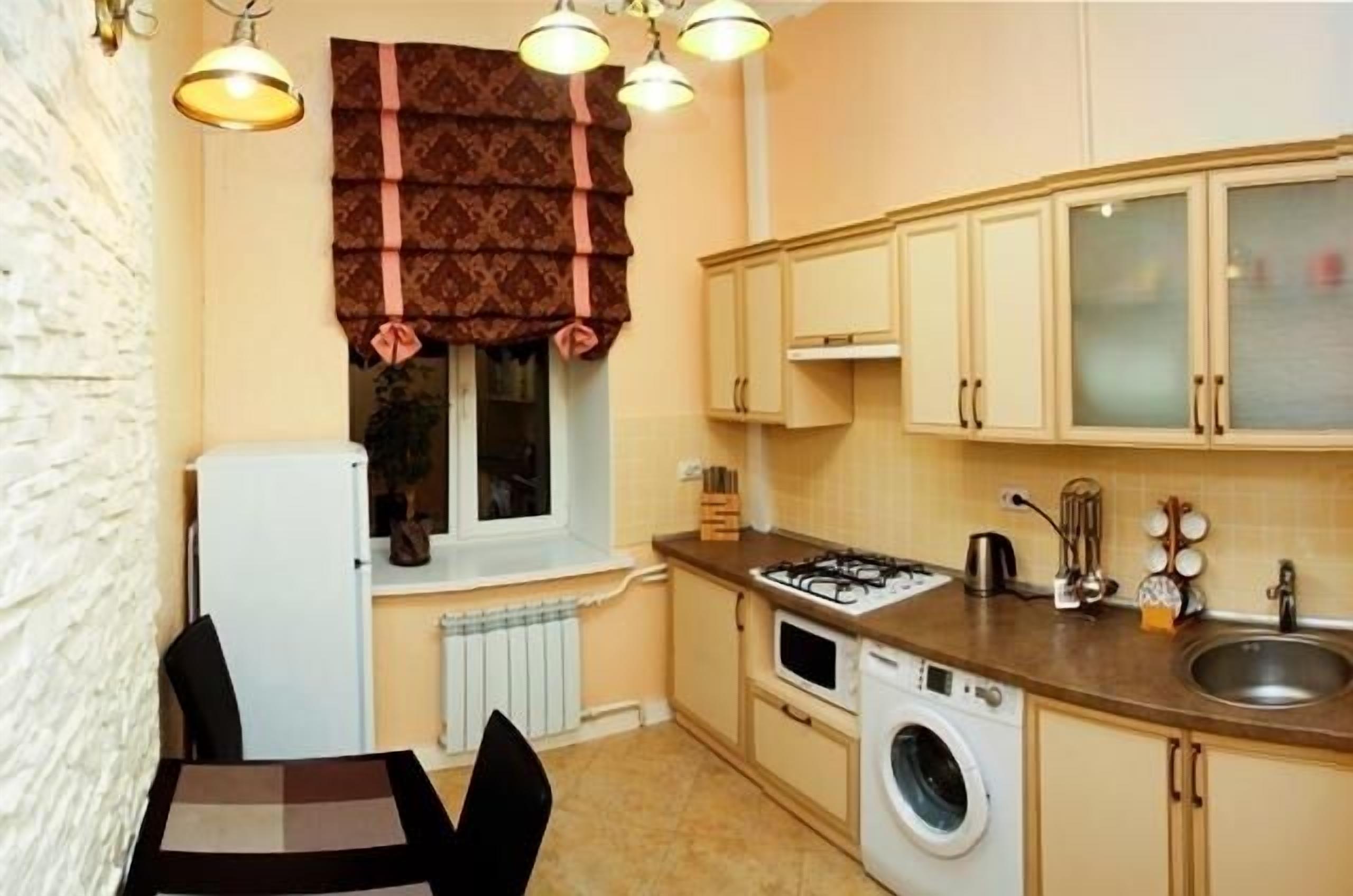 A compact kitchen with a washing machine, a stove, and a sink.