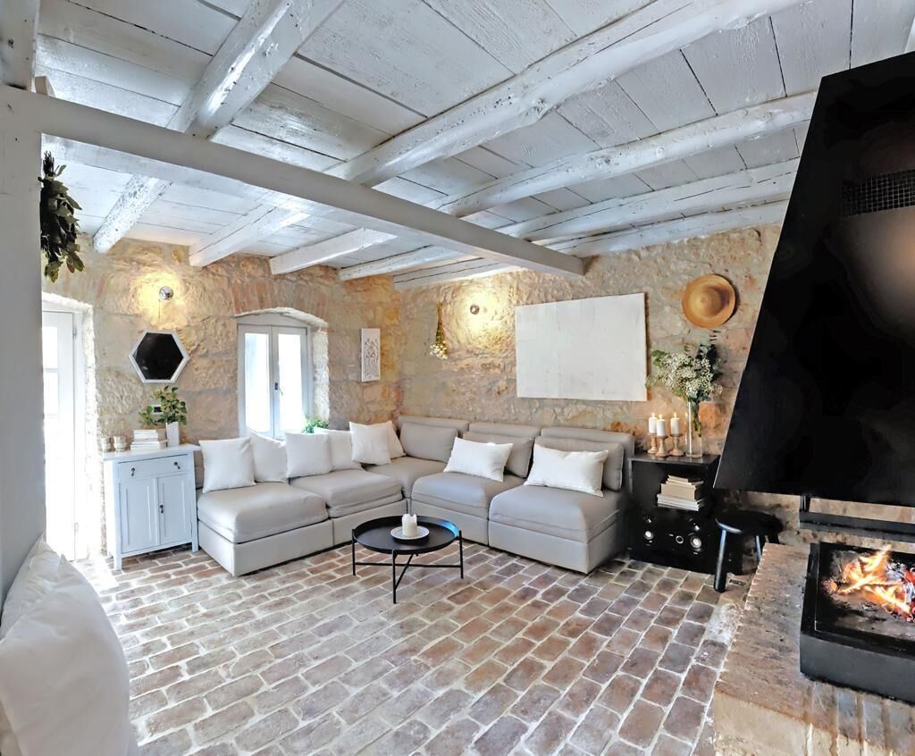 Un salon chaleureux avec un mur en pierre, une cheminée, un canapé et un téléviseur.
