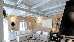A cozy living room with a stone wall, a fireplace, a sofa, and a TV. - Villa Alisia, Wunderschönes Natursteinhaus mit Pool bei Pore? (Vizinada)