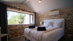 A bedroom with a stone wall, a bed with white bedding, and a window with curtains. - Villa Alisia, Wunderschönes Natursteinhaus mit Pool bei Pore? (Vizinada)